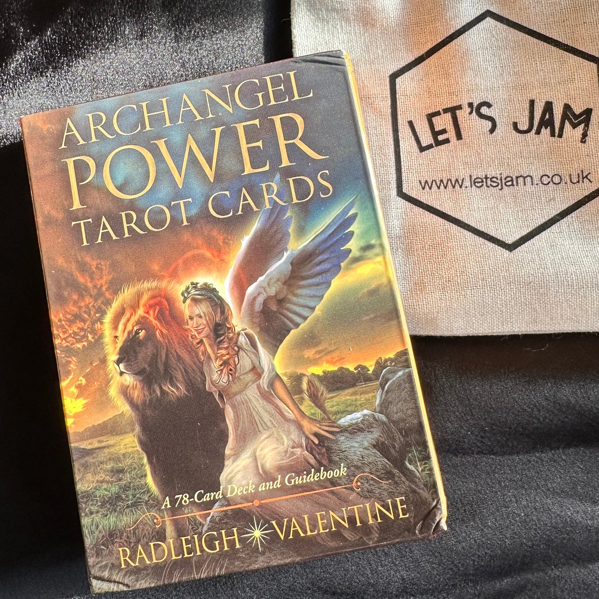 Archangel Power tarot deck box by Radleigh Valentine beside a cream drawstring bag on black fabric - Let's Jam, Camden Market London