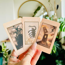 Load image into Gallery viewer, Hand fanning out three cream-toned "Lucid Dreams" tarot cards with minimalist line-art illustrations, including The Tower, in front of houseplants and a round mirror - Let's Jam collection