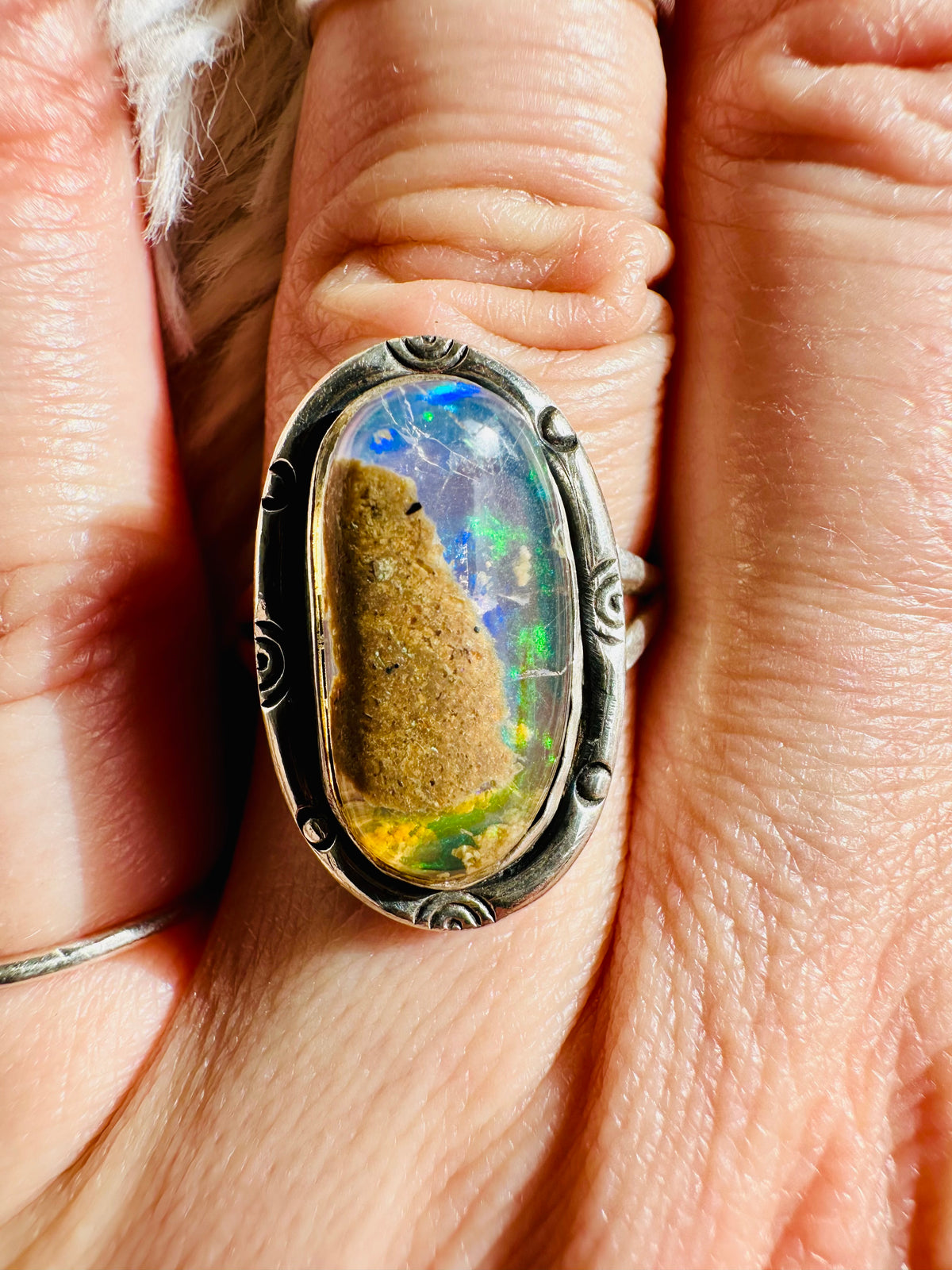 Handmade 925 sterling silver ring with an oval matrix opal showing bright green and blue fire, ornate scrollwork silver bezel, one-of-a-kind gemstone ring - Let's Jam jewellery collection
