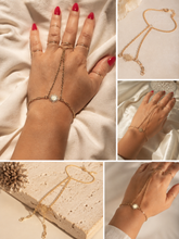 Load image into Gallery viewer, Close-up of a gold sun hand chain bracelet with a delicate finger ring and fine chains, worn on a hand with red nails against soft cream fabric.