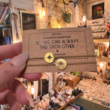 Load image into Gallery viewer, Hand holding two gold compass charm bracelets on their kraft gift card - Let's Jam jewellery, Camden Town London