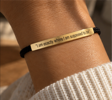 Load image into Gallery viewer, Gold engraved bar bracelet worn on the wrist over black cord - Let's Jam jewellery, Camden Market London
