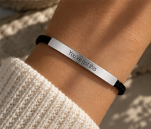 Load image into Gallery viewer, A close-up of a person's wrist wearing a silver bar bracelet engraved with the words 'You've got this' on a black cord, styled with a cream knit sleeve.