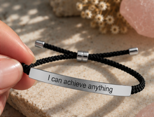 Load image into Gallery viewer, Hand holding a black cord bracelet with a silver engraved plate - Let's Jam jewellery, Camden Town