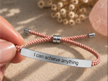 Load image into Gallery viewer, Hand holding a pink cord bracelet with a silver engraved bar - Let's Jam jewellery, Camden Market London
