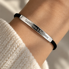 Load image into Gallery viewer, Black cord bracelet with a silver Gratitude and Resilience bar, worn - Let's Jam jewellery, Camden Market, London