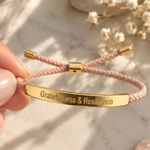 Load image into Gallery viewer, Hand holding a pink cord bracelet with a gold engraved bar and dried flowers - Let's Jam, Camden Town London