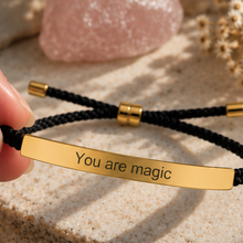 Load image into Gallery viewer, Black cord bracelet with a gold You Are Magic bar on a stone surface - Let's Jam, Camden Market London