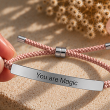 Load image into Gallery viewer, Hand holding a pink cord bracelet with a polished silver You Are Magic bar - Let's Jam jewellery, Camden Market London