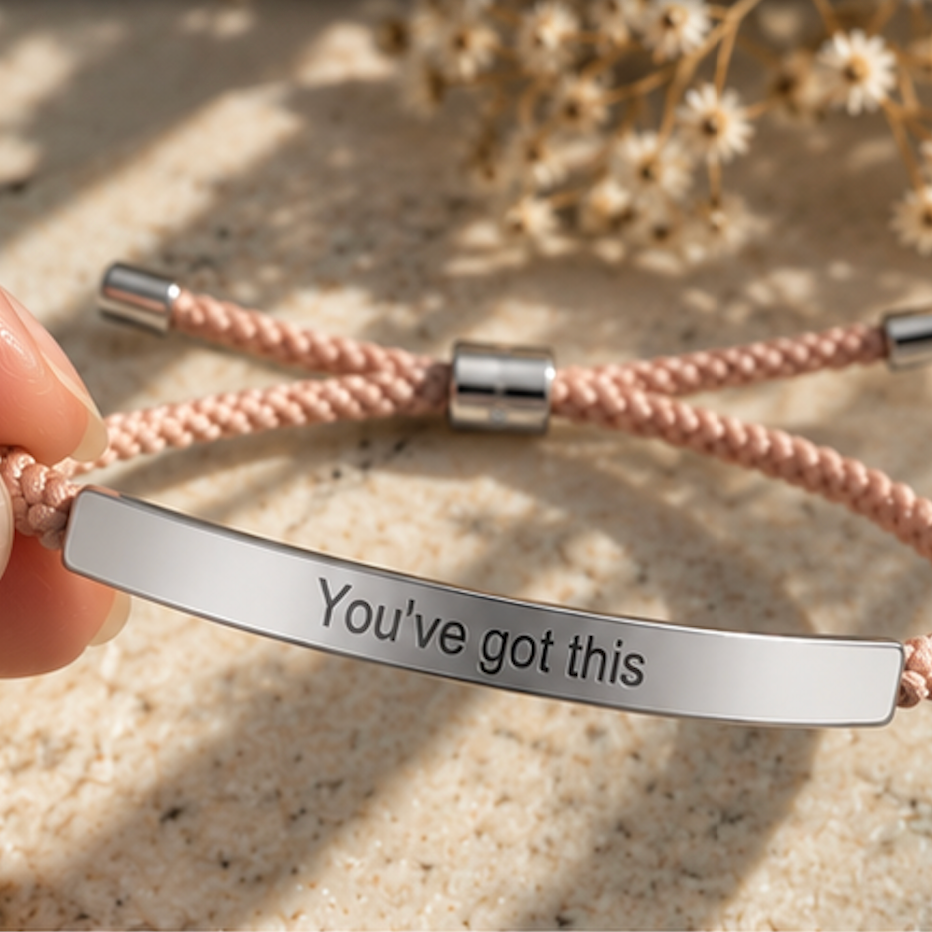 Hand holding a pink cord bracelet with a silver You've Got This bar - Let's Jam, Camden Town London