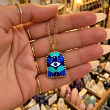 Load image into Gallery viewer, Gold arch pendant with a blue evil eye held in the hand - Let's Jam, Camden Town London