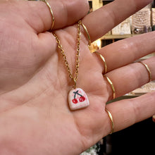 Load image into Gallery viewer, Cherry ceramic pendant on a gold chain held in the hand - Let's Jam, Camden Market
