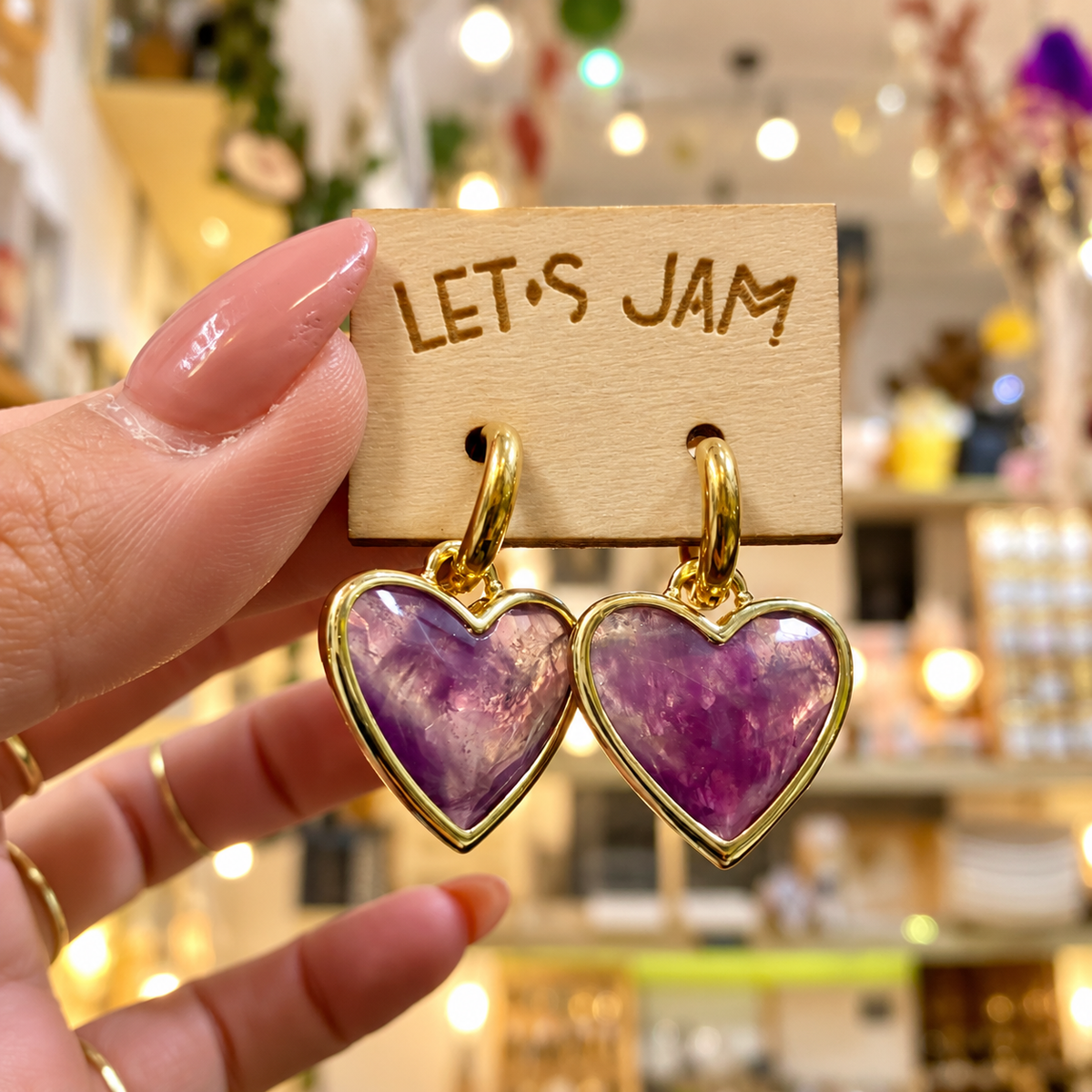 Amethyst crystal heart earrings held in the hand in the shop - Let's Jam, Camden Town