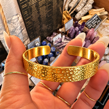 Load image into Gallery viewer, Front of the hammered gold cuff held up - Let's Jam jewellery, Camden Market, London