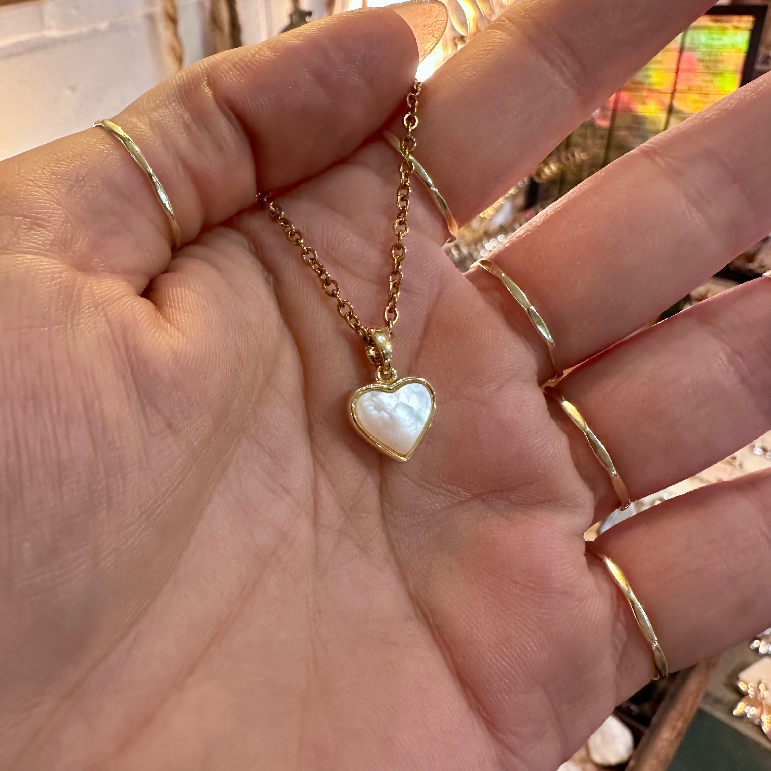 Gold framed mother of pearl heart pendant held in the hand - Let's Jam, Camden Market, London