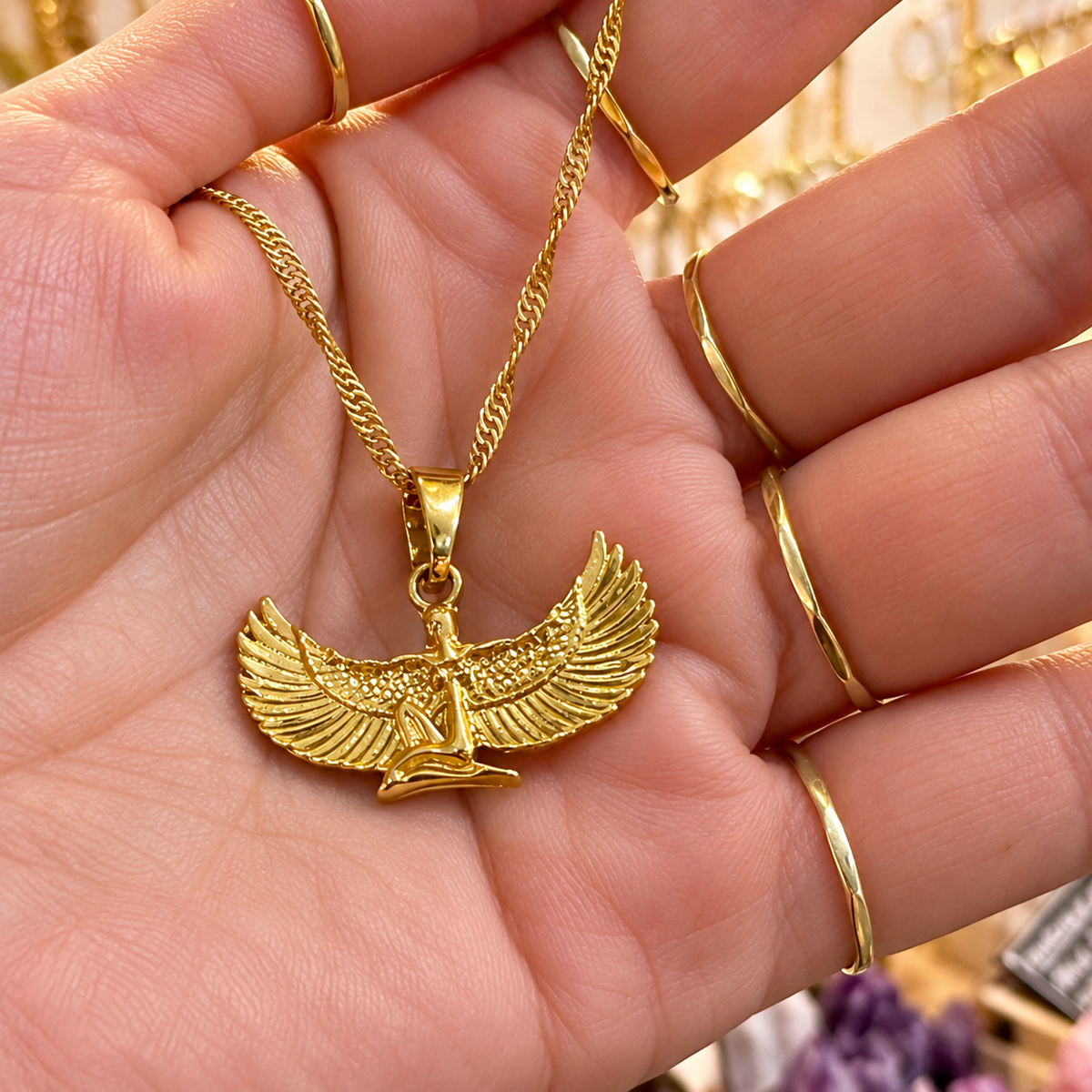 Gold winged goddess Isis pendant necklace held in the hand - Let's Jam, Camden Market