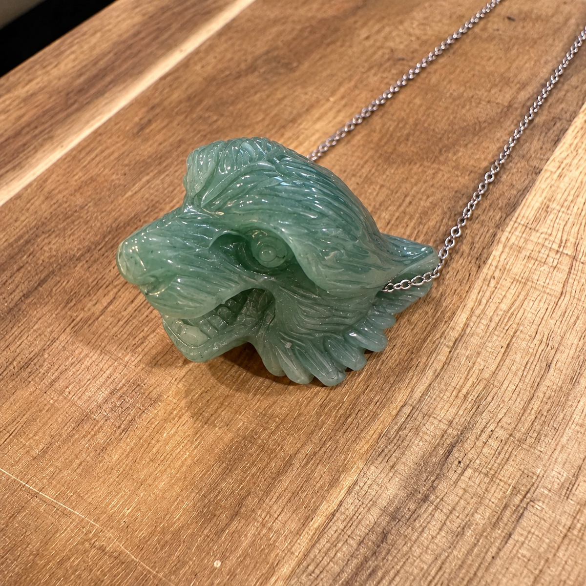 Hand carved jade tiger head on a silver chain laid on wood - Let's Jam, Camden Market
