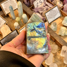 Load image into Gallery viewer, Labradorite obelisk held in front of crystal displays - Let's Jam, Camden Market, London