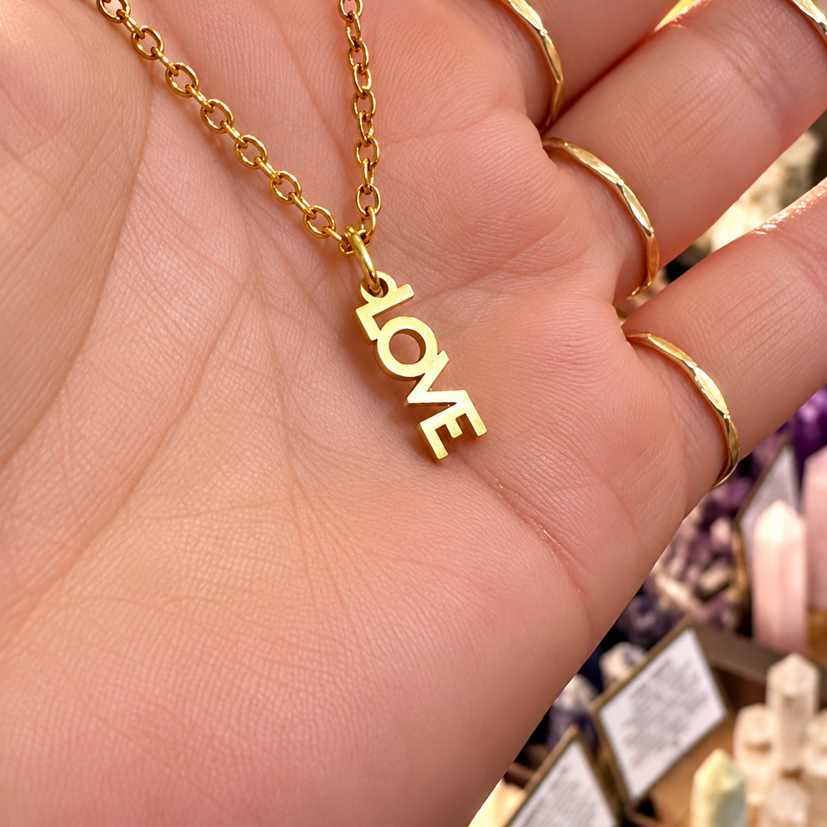 Gold LOVE word necklace held in the hand - Let's Jam, Camden Town London