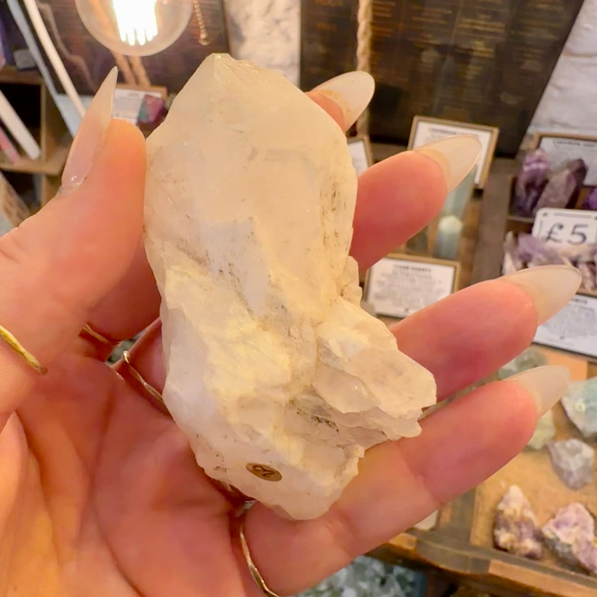 Raw milky quartz point held in the hand in the crystal shop - Let's Jam, Camden Town
