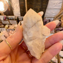 Load image into Gallery viewer, Creamy white raw milky quartz point held up to show its rough texture - Let's Jam, Camden Market London