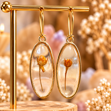 Load image into Gallery viewer, Oval resin earrings with a single real orange flower on its stem, on a gold stand - Let's Jam, Camden Town