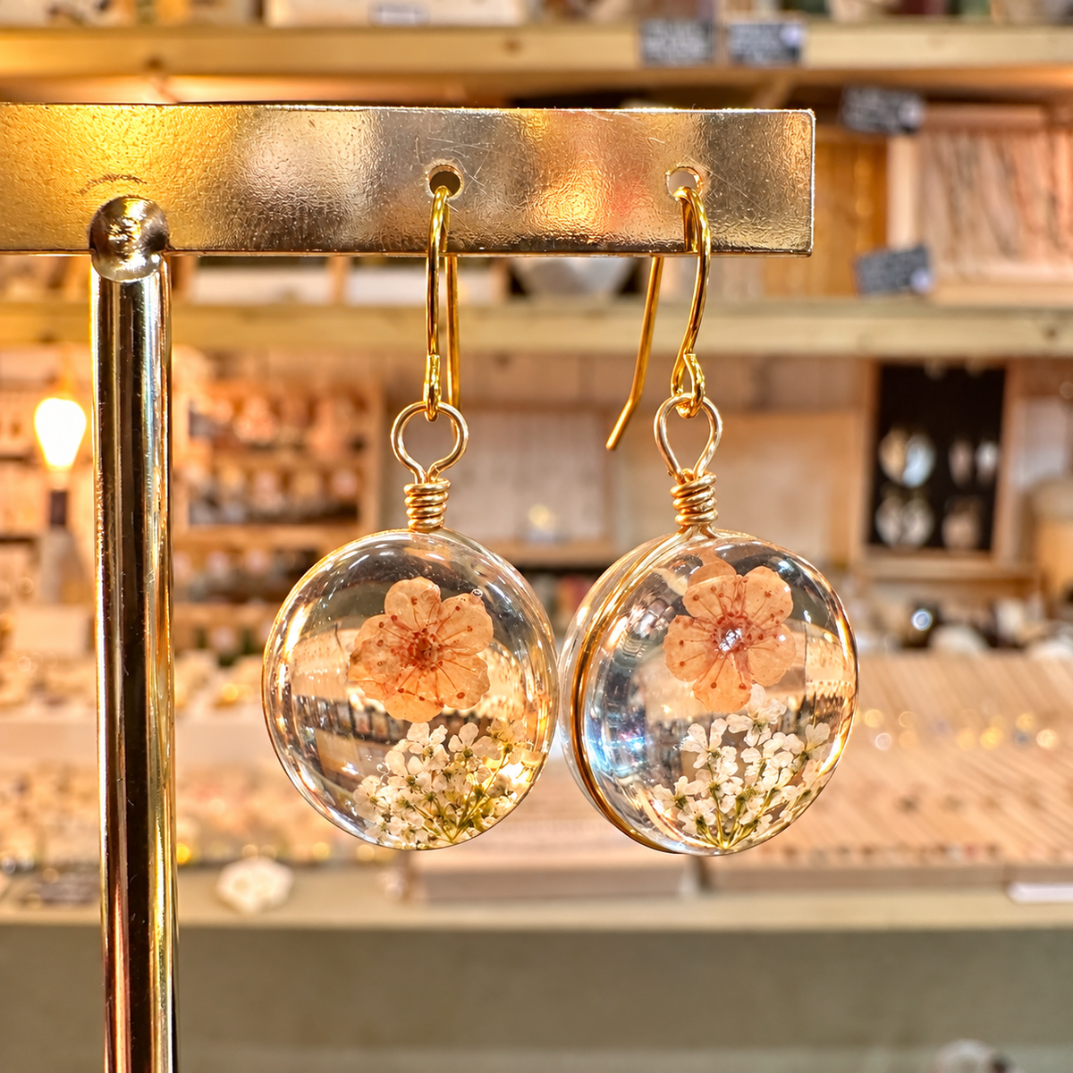 Round resin earrings with a real peach flower and tiny white blossoms on a gold stand - Let's Jam jewellery, Camden Town London