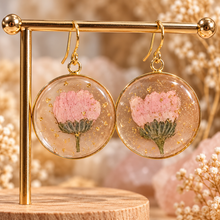 Load image into Gallery viewer, Round resin earrings with a real pink flower and gold flecks hanging on a gold stand - Let's Jam, Camden Market London