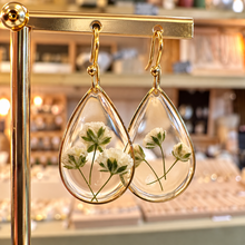 Load image into Gallery viewer, Teardrop resin earrings with real white flowers and green stems on a gold stand in the shop - Let's Jam jewellery, Camden Market London