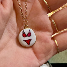 Load image into Gallery viewer, Red bikini ceramic pendant on a gold chain held in the hand - Let's Jam, Camden Market