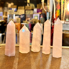 Load image into Gallery viewer, Five soft pink rose quartz towers standing in a row in the shop - Let's Jam, Camden Market London