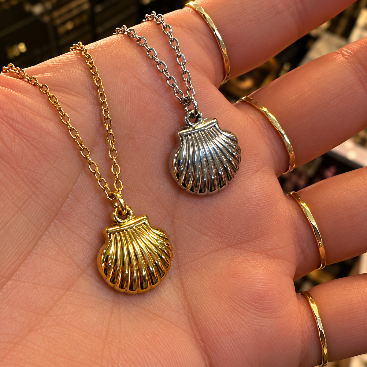 Gold and silver scallop shell pendants held in the hand - Let's Jam jewellery, Camden Market, London