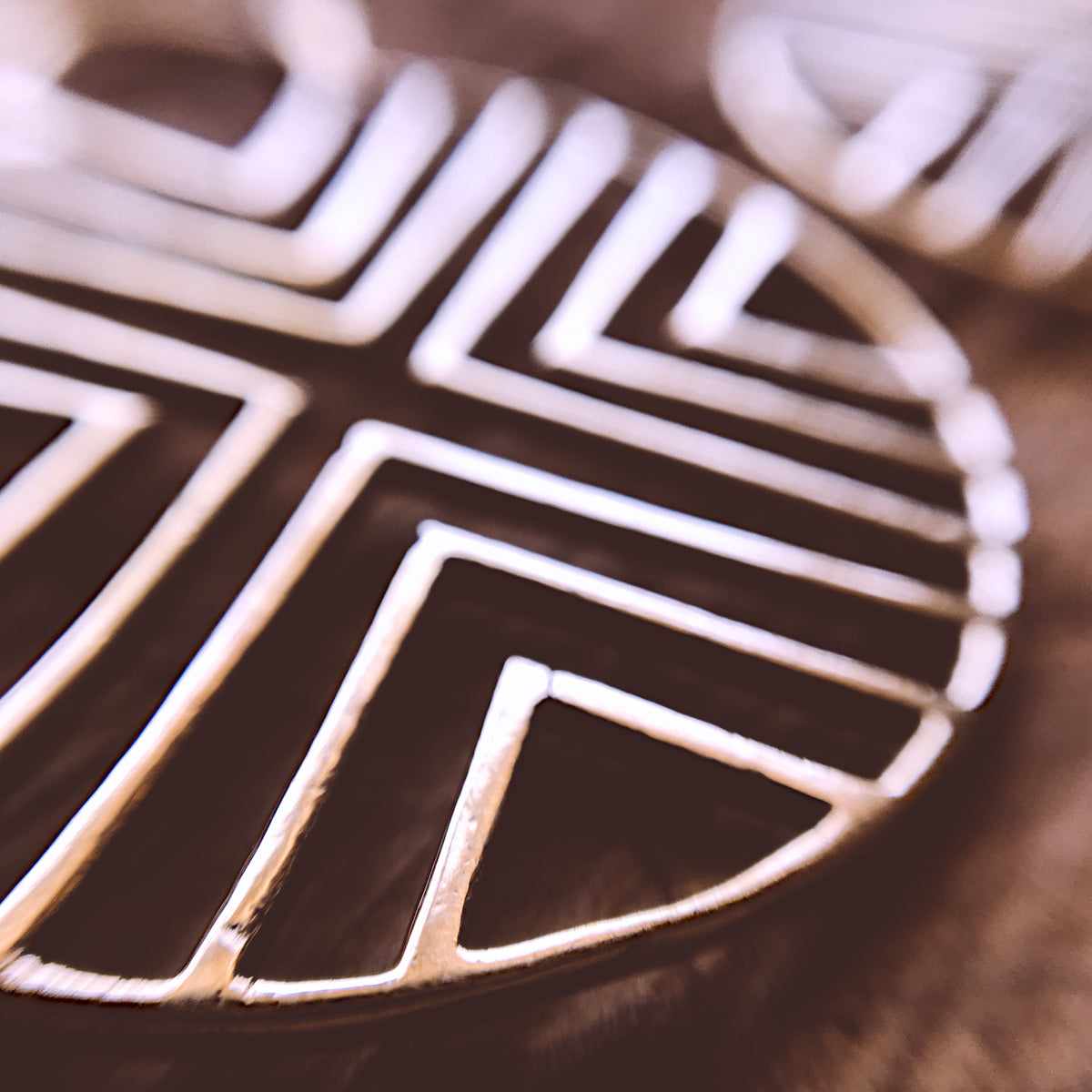 Close-up of a round brass earring with a cut-out geometric triangle pattern, ethnic-inspired design - Let's Jam jewellery collection