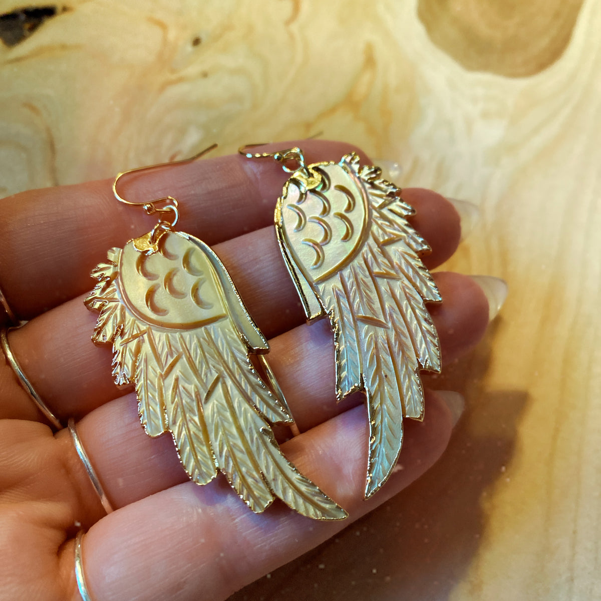 Golden-yellow shell angel wing earrings laid side by side on wood - Let's Jam jewellery, Camden Town