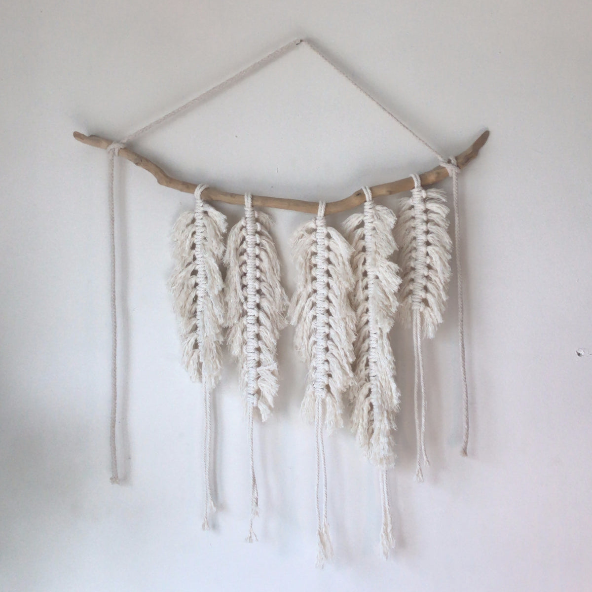 Handmade macrame wall hanging with feather-like fringed cotton strands on a branch - Let's Jam home decor, Camden Market