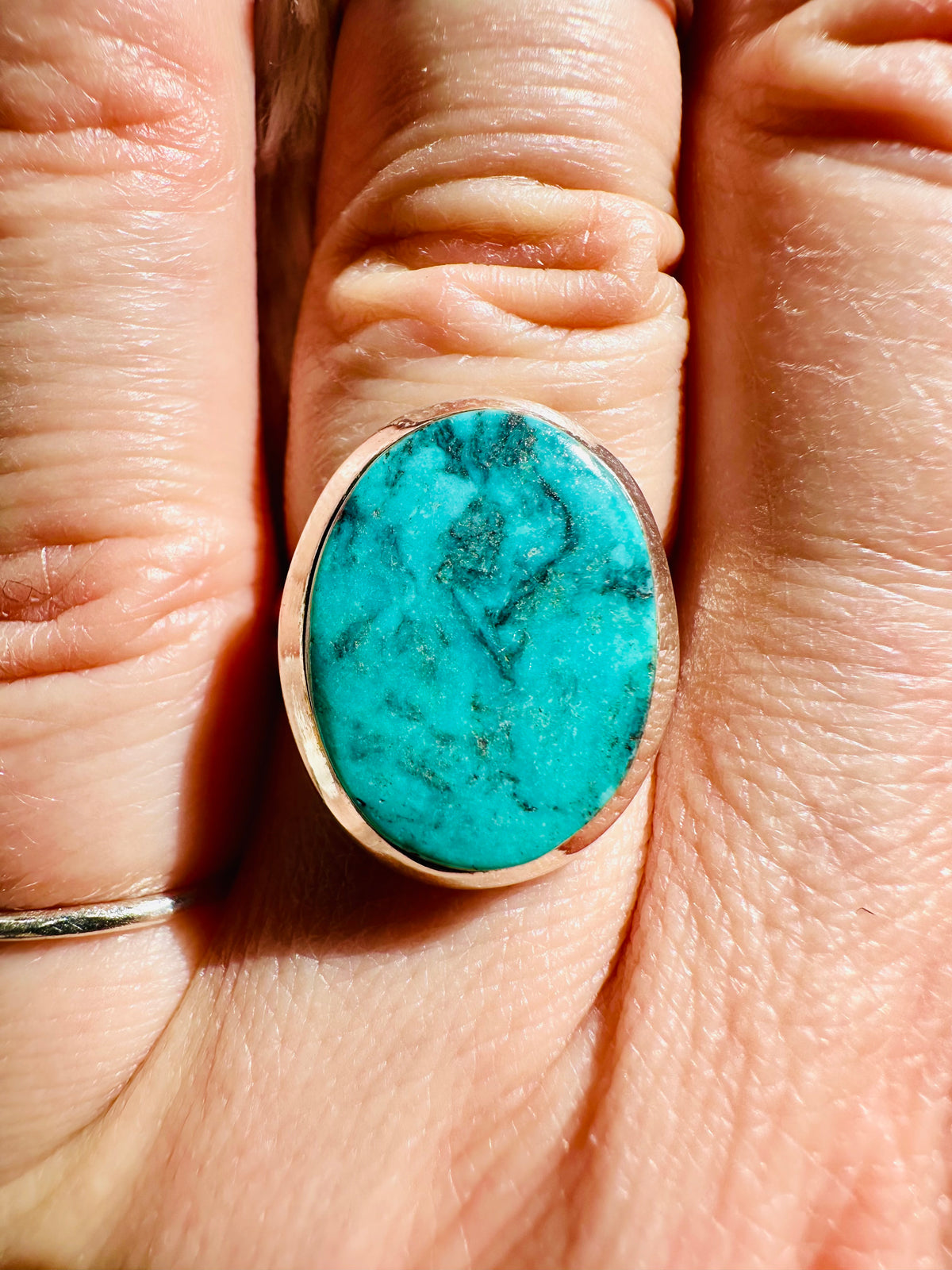 Large oval turquoise cabochon ring with dark spider-web matrix, set in a smooth copper-toned metal bezel - Let's Jam jewellery collection