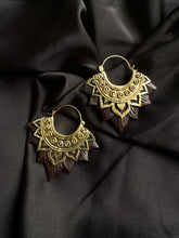 Load image into Gallery viewer, Pair of ornate gold-tone hoop earrings with an intricately carved dark wood lotus flower petal fringe, displayed on dark satin fabric - Let's Jam jewellery collection
