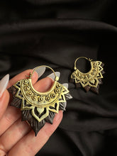 Load image into Gallery viewer, HANDCARVED_LOTUS_EARRINGS_-_WOOD_BRASS A pair of gold-colored brass earrings with a sculpted wood lotus flower design, displayed against a black fabric background.
