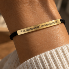 Load image into Gallery viewer, Gold engraved bar bracelet worn on the wrist over black cord - Let's Jam jewellery, Camden Market London
