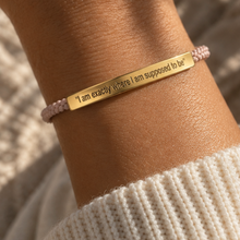 Load image into Gallery viewer, Pale pink cord bracelet with a gold engraved bar, worn with a knit jumper - Let's Jam, Camden Market
