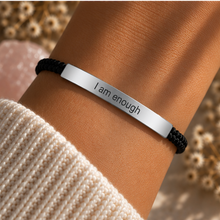 Load image into Gallery viewer, Black cord bracelet with a silver I Am Enough bar and a knit sleeve behind - Let's Jam, Camden Town
