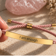 Load image into Gallery viewer, Hand holding a pink cord bracelet with a gold I Am Enough bar - Let's Jam jewellery, Camden Market London
