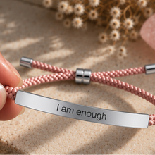 Load image into Gallery viewer, Hand holding a pink cord bracelet with a silver I Am Enough bar - Let's Jam jewellery, Camden Market, London
