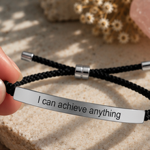 Load image into Gallery viewer, Hand holding a black cord bracelet with a silver engraved plate - Let's Jam jewellery, Camden Town
