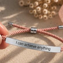 Load image into Gallery viewer, Hand holding a pink cord bracelet with a silver engraved bar - Let's Jam jewellery, Camden Market London
