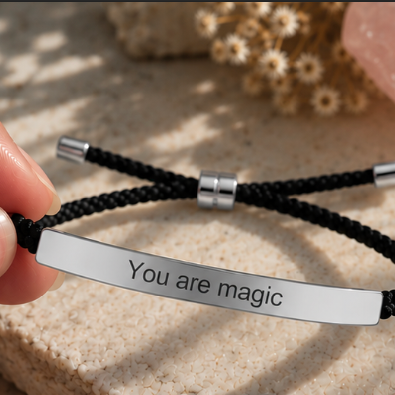 Hand holding a black cord bracelet with a silver You Are Magic bar - Let's Jam jewellery, Camden Town