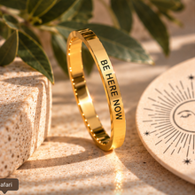 Load image into Gallery viewer, Gold 'Be here now' ring on a beige surface with decorative leaves - Let's Jam jewellery, Camden Market
