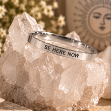 Load image into Gallery viewer, Silver affirmation ring engraved 'Be here now' displayed on quartz - Let's Jam jewellery, Camden Market
