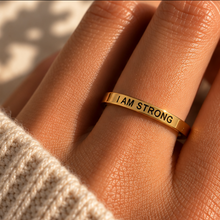 Load image into Gallery viewer, Hand wearing the gold 'I am strong' affirmation ring in sunlight - Let's Jam jewellery, Camden Town
