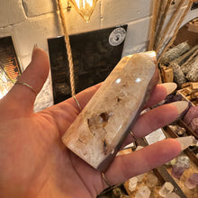 Load image into Gallery viewer, Agate tower held in the hand showing its cream side and sparkling pocket - Let's Jam, Camden Town
